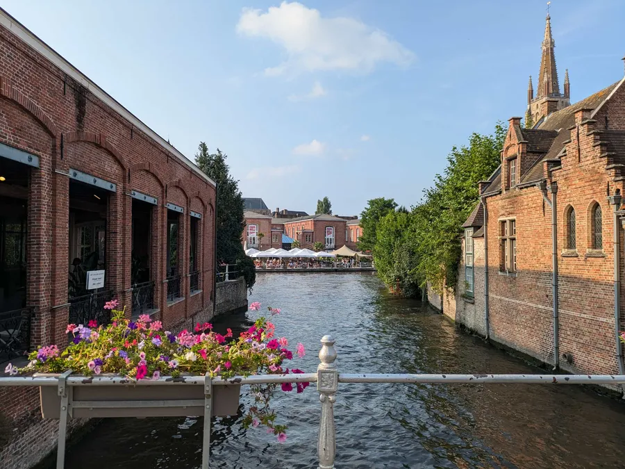 One of the canals in Bruges, with flowers and al-fresco dining in the background